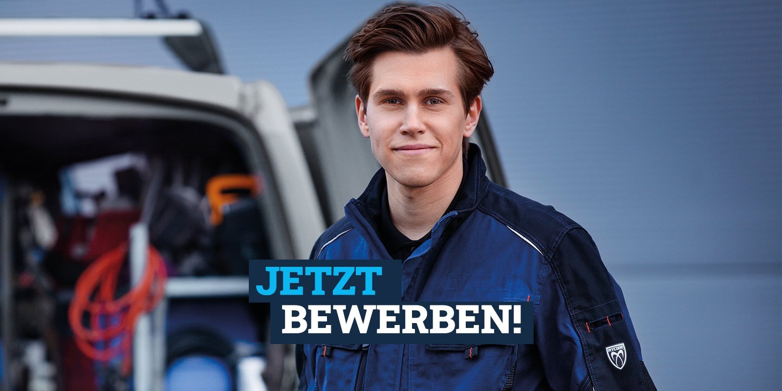 Ein Auszubildener der vor einem Firmenbulli steht und Lächelt, mit dem Slogan: Jetzt Bewerben!